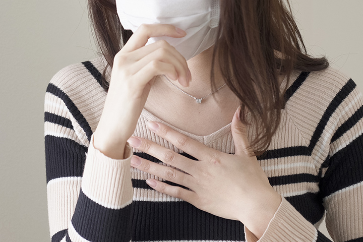 咳き込んでいるマスクをした女性